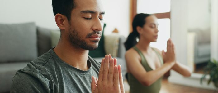 Couple, man and namaste with meditation in home for holistic wellness, mindfulness and relax on flo